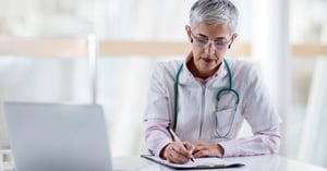 mature-doctor-filing-medical-documents-at-doctors-office_social